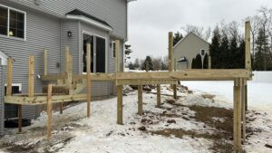 Custom Deck Construction in progress, showing the foundational framing and structure layout during winter.